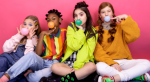 Four girls sitting on the floor and chewing bubble gum.
